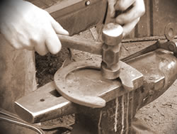 Hammering horse shoe on anvil
